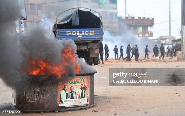 Fire burns as Guinean riot police officers patrol following clashes with protesters in a district of Conakry on November 21, 2017. Thousands of...