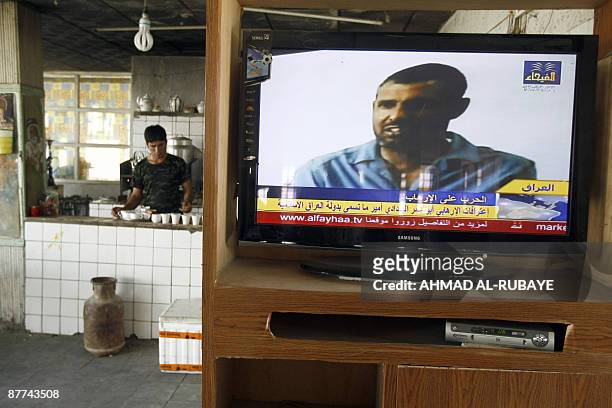 Coffee shop workers lays out cups while a local Iraqi television channel shows the confession of an Iraqi man allegedly Abu Omar al-Baghdadi, said to...