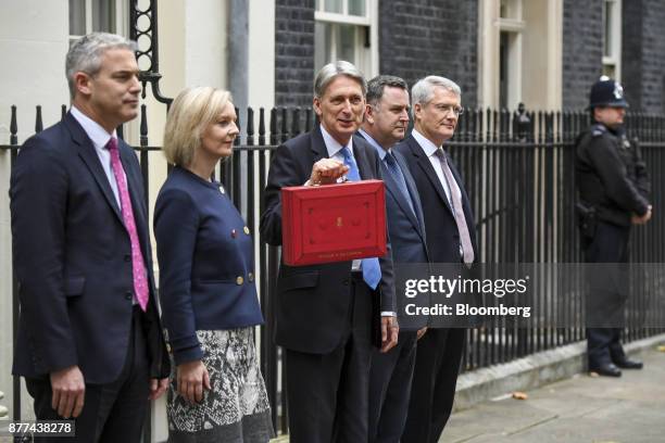 Philip Hammond, U.K. Chancellor of the exchequer, center, holds the dispatch box containing the budget, as he poses for photographs with, left to...