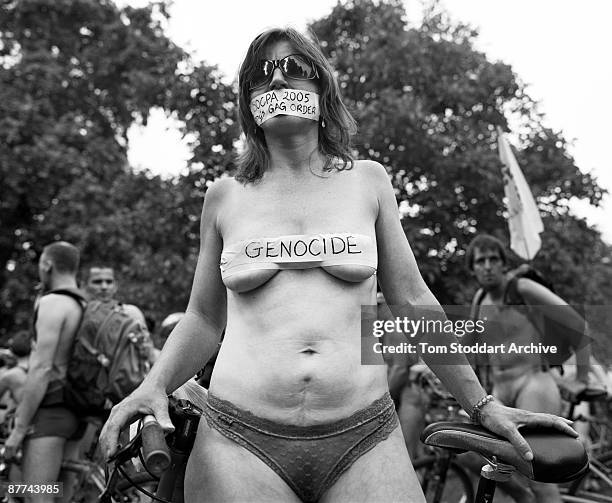 Woman cyclist with a 'genocide' sticker on her breasts before the start of the annual London Naked Bike Ride, June 2007. A gag over her mouth refers...