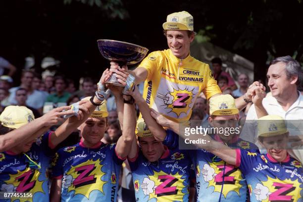 Cyclist Greg Lemond wearing the yellow jersey holds the trophy, 22 July 1990 after winning the 21th stage of the 79th Tour de France cycling race,...