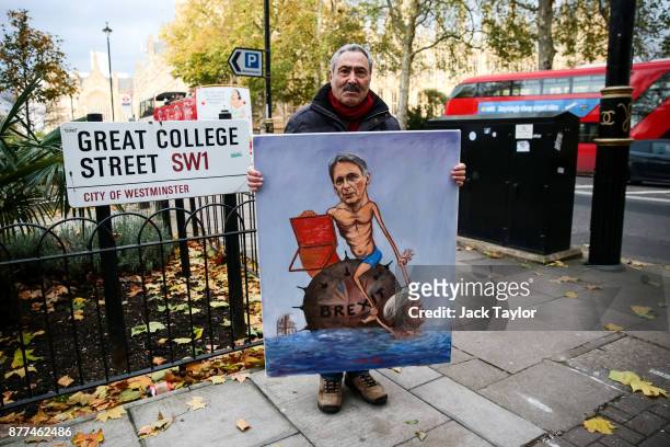 Political artist Kaya Mar poses with a painting depicting the Chancellor Philip Hammond and Prime Minister Theresa May on November 22, 2017 in...