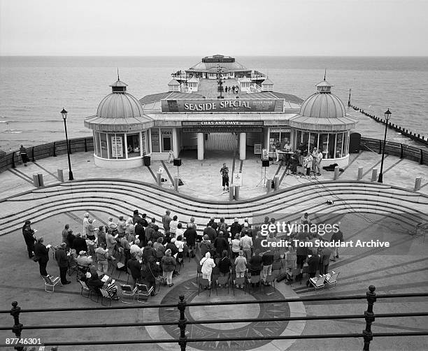 Church service is held on Cromer Pier, North Norfolk, July 2007. Behind them, a poster advertises a concert by Rockney duo Chas & Dave.