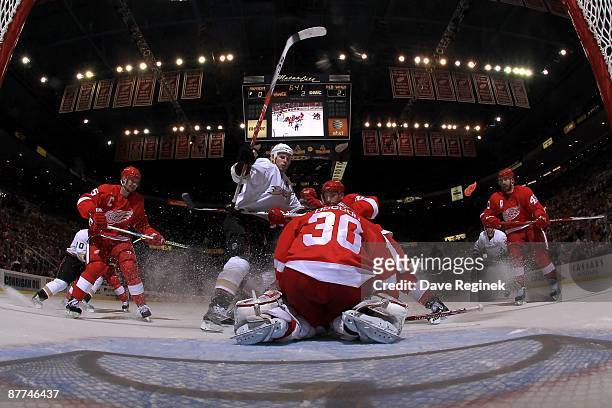 Ryan Getzlaf of the Anaheim Ducks charges the net as Chris Osgood of the Detroit Red Wings covers the puck and defensman Brian Rafalski puts a body...