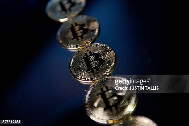 Gold plated souvenir Bitcoin coins are arranged for a photograph in London on November 20, 2017. - Bitcoin, a type of cryptocurrency, uses...
