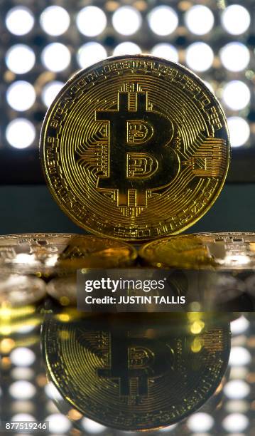 Gold plated souvenir Bitcoin coins are arranged for a photograph in London on November 20, 2017. - Bitcoin, a type of cryptocurrency, uses...