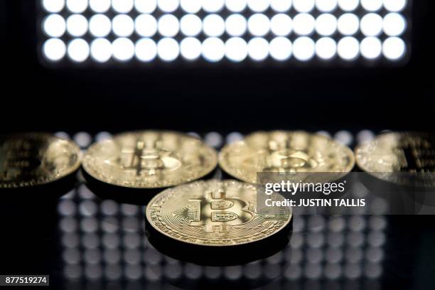 Gold plated souvenir Bitcoin coins are arranged for a photograph in London on November 20, 2017. - Bitcoin, a type of cryptocurrency, uses...