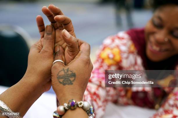 Tammy Johnson, one of a dozen volunteer from Bennett Career Institute, massages the hand of Shelly 'Smiley' Baltimore during a manicure as part of...