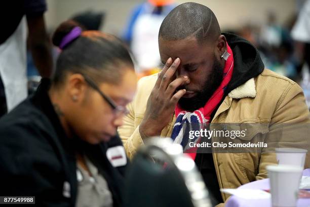 Volunteers and guests bow their heads in prayer during The Salvation Army and Safeway's 18th annual "Feast of Sharing," at the Walter E. Washington...