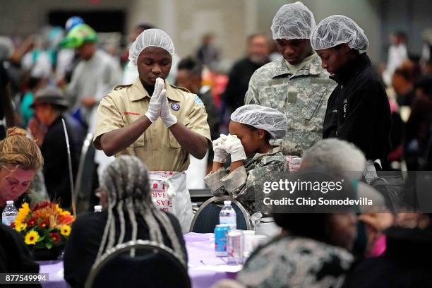 Volunteers and guests bow their heads in prayer during The Salvation Army and Safeway's 18th annual "Feast of Sharing," at the Walter E. Washington...