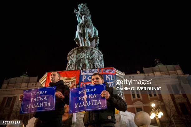 Two men stand in front of the statue of Prince of Serbia Mihailo Obrenovic, as they pose with banners reading "Ratko Mladic Boulevard" during a...