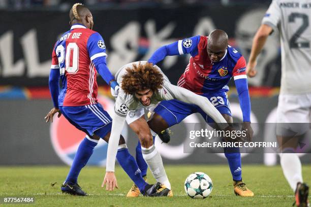 Manchester United's Belgian midfielder Marouane Fellaini vies for the ball with Basel's Ivorian midfielder Geoffroy Serey Die and Basel's Colombian...