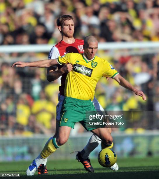 Per Mertesacker of Arsenal and Steve Morison of Norwich City wrestle for the ball during a Barclays Premier League match at Carrow Road on November...
