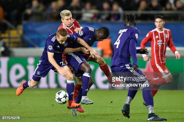 Anderlecht's French midfielder Adrien Trebel and Anderlecht's French defender Dennis Appiah vie with Bayern Munich's Polish forward Robert...