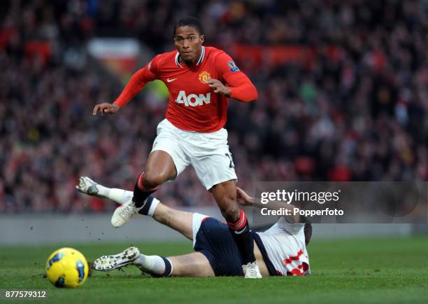 Antonio Valencia of Manchester United avoids the sliding tackle from Sam Ricketts of Bolton Wanderers during a Barclays Premier League match at Old...