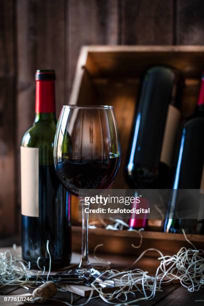 wineglas and red wine bottle shot rustic wooden table - wine bottle transport stock pictures, royalty-free photos & images