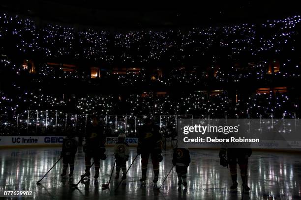 Anaheim Ducks bow their heads as fans turn on their cell phone flashlights during a moment of silence for Hockey Fights Cancer before the game...
