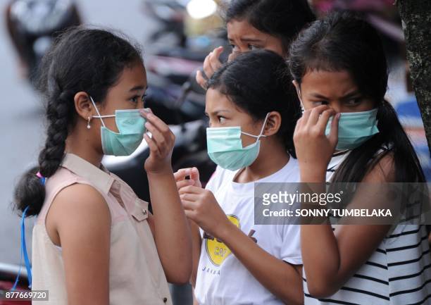 Young people put on masks due to ash in the air from Mt. Agung volcano, at a traditional market in the Rendang sub-district of Karangasem Regency on...