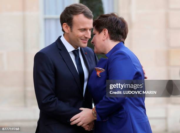 French President Emmanuel Macron welcomes Polish Prime Minister Beata Szydlo before a meeting at the Elysee Palace in Paris on November 23, 2017. /...