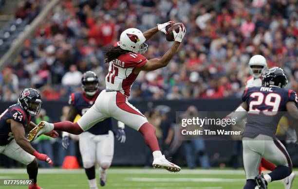 Larry Fitzgerald of the Arizona Cardinals catches a pass in the first half defended by Jelani Jenkins of the Houston Texans and Andre Hal at NRG...