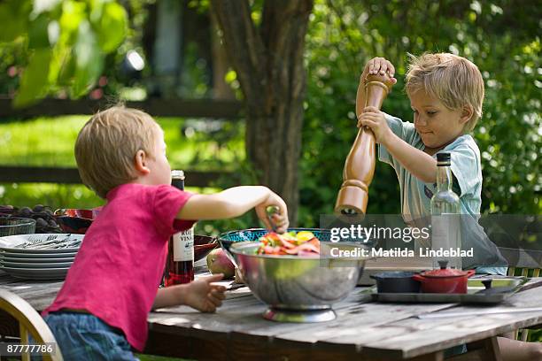 two children making a salad in the garden sweden. - pepper mill stockfoto's en -beelden