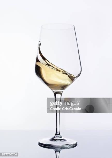 white wine swirling into glass - white wine stock-fotos und bilder