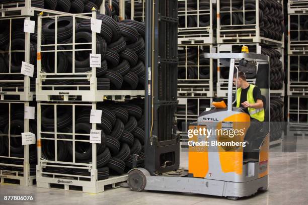 Worker uses a front-loader to move cages of new automobile tires around a storage facility at the Continental AG tire plant in Kaluga, Russia, on...