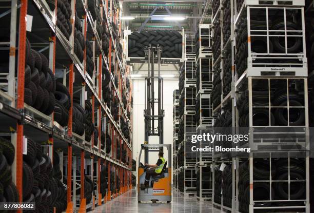 Worker uses a front-loader to move a cage of new automobile tires from the top section of the rack storage facility at the Continental AG tire plant...