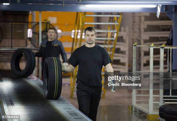 Workers role finished automobile tires from the end of the conveyor belt in a storage area at the Continental AG tire plant in Kaluga, Russia, on...