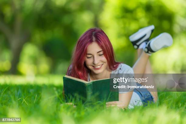 jeune femme lisant le livre posé sur l’herbe. - fille lire gazon photos et images de collection