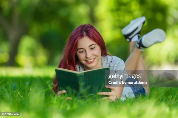 jeune femme lisant le livre posé sur l’herbe. - fille lire gazon photos et images de collection
