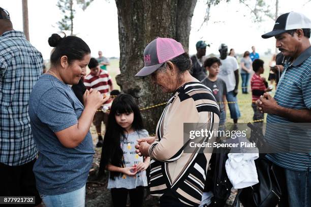 Family members pray before the start of the annual Thanksgiving in the Park gathering where residents of the farm worker community of Immokalee are...