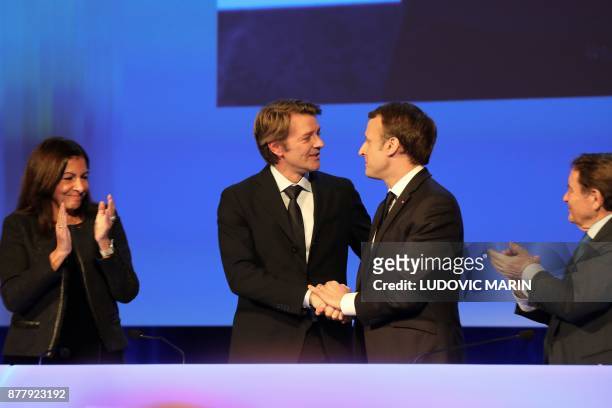 French President Emmanuel Macron and Mayor of Troyes and President of the Association of Mayors of France Francois Baroin shake hands next to by...