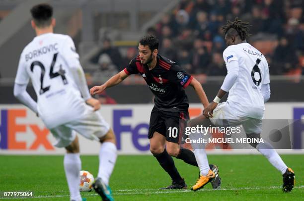 Milan's German midfielder Hakan Calhanoglu vies with Austria Wien's from Ghana defender Abdul Mohamed during the UEFA Europa League group D football...