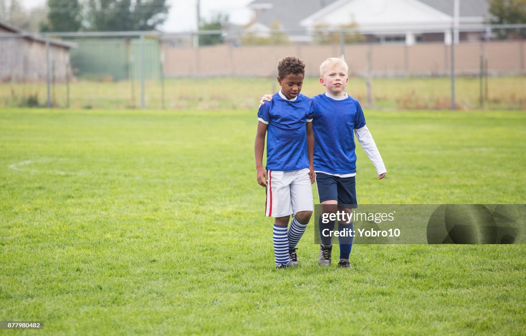 Two soccer teammates walking off the field after a loss