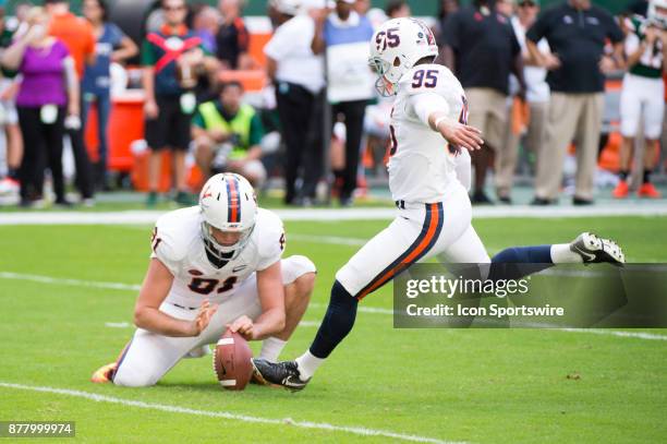 Virginia Cavaliers Kicker A.J. Mejia kicks an extra point as Virginia Cavaliers Kicker Nash Griffin holds the ball during the college football game...