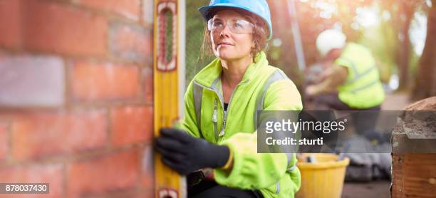 female brickie checking her levels - builder apprenticeship stock pictures, royalty-free photos & images