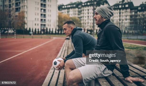 football players sitting on a bench - soccer sideline stock pictures, royalty-free photos & images