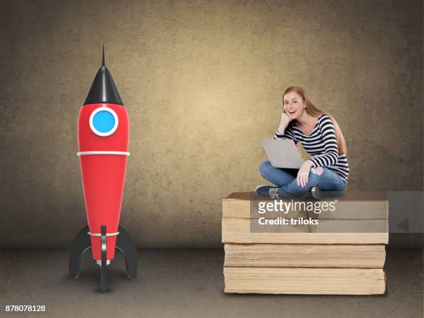excited female student with laptop on stack of books - rocket book stock pictures, royalty-free photos & images