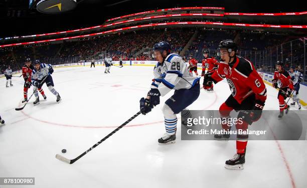 Etienne Verrette of the Quebec Remparts and Vincent Milot-Ouellet of the Chicoutimi Sagueneens battle for the puck during the first period their...