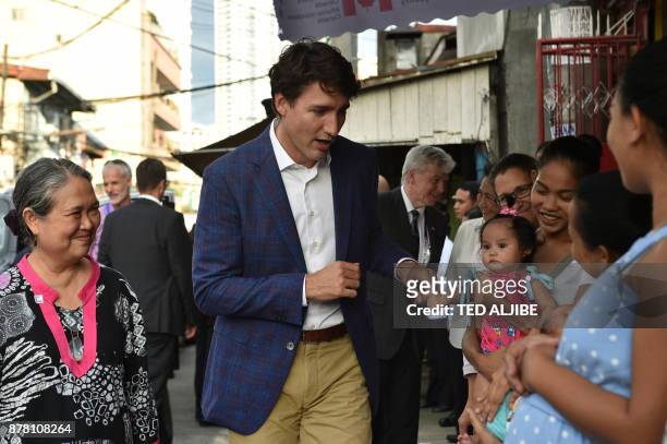 This photo taken on November 12, 2017 shows Canada's Prime Minister Justin Trudeau greeting mothers at a clinic run by the non-governmental...