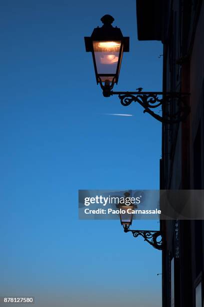 two lanterns illuminated at blue hour in tuscania, italy - ferro battuto foto e immagini stock