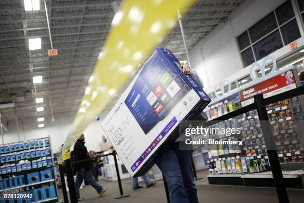 Shopper carries an Insignia Roku TV television at a Best Buy Co. Store in Louisville, Kentucky, U.S., on Thursday, Nov. 23, 2017. The highly...
