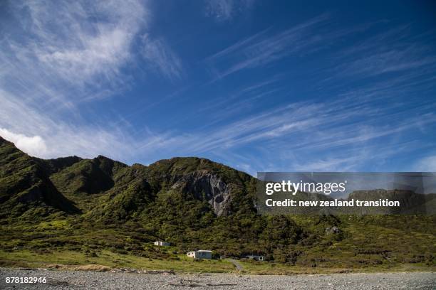 seaside bach with blue sky and thin lines of white clouds across sky, wairarapa, nz - bach new zealand imagens e fotografias de stock