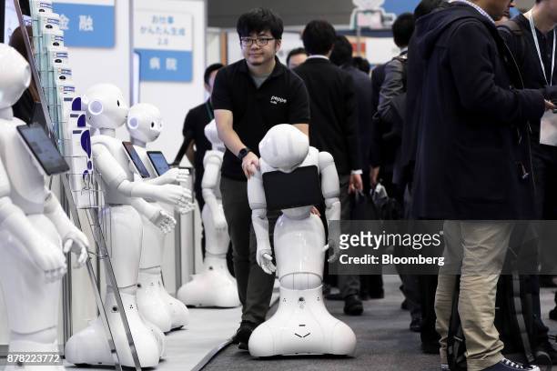 An attendant pushes a SoftBank Group Corp. Pepper humanoid robot at the SoftBank Robot World 2017 in Tokyo, Japan, on Tuesday, Nov. 21, 2017....