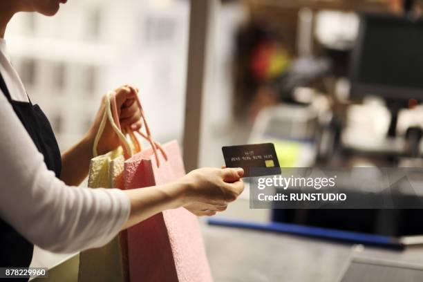 close up of woman paying with credit card in store - shopping bag in hand stockfoto's en -beelden