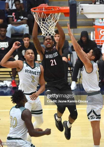 Malik Pope of the San Diego State Aztecs drives past Justin Strings and Jeff Wu of the Sacramento State Hornets for a basket in the second half of...