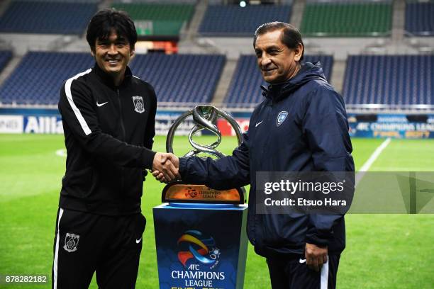 Head coach Takafumi Hori of Urawa Red Diamonds and head coach Ramon Diaz of Al Hilal shake hands in front of the trophy during a press conference...