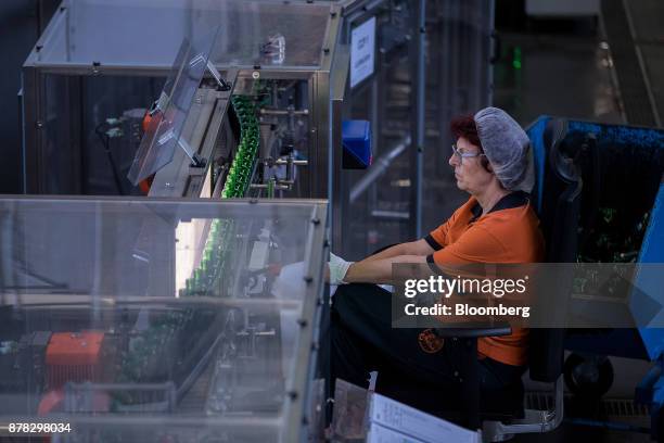 An employee carries out quality checks on empty green bottles as they move along a conveyor inside the Mast-Jaegermeister SE fruit liquor bottling...