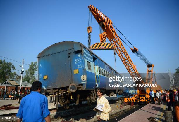 Derailed coach of an Indian express train is lifted by a crane offthe tracks near Manikpur railway station in Uttar Pradesh on November 24, 2017....